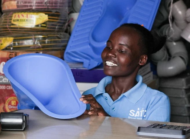 Smiling woman holding a SATO toilet in shop